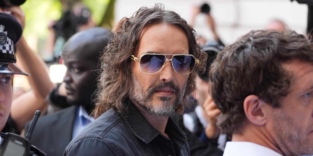 Russell Brand yn cyrraedd y llys