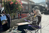 Rachel yn paentio tu allan i&#039;r Prince&#039;s Cafe yn Pontypridd