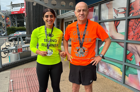 Naz ac un o&#039;i rhedwr tywys Mark yn sefyll gyda&#039;i medalau hanner marathon Caerdydd