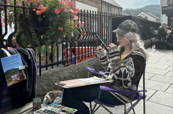 Rachel yn paentio tu allan i&#039;r Prince&#039;s Cafe yn Pontypridd