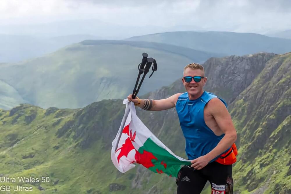 Gareth gyda banner Cymru wrth neud un o'i rases