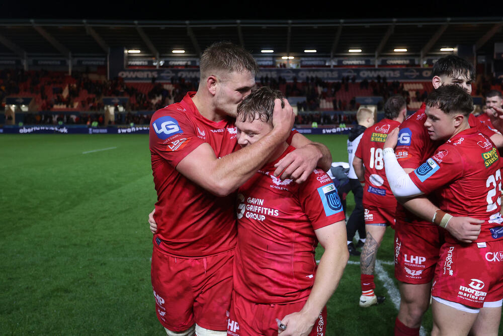 Taine Plumtree a Sam Costelow yw dau chwaraewr sydd wedi elwa o'r cynllun